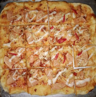 Birkaç küçük parçayla kare pizza. Tavuklu ve domatesli ev yapımı lezzetli bir pizza..