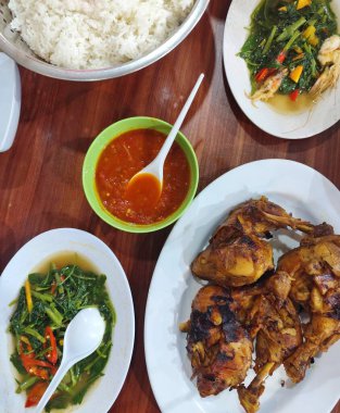 Bir tabak sotelenmiş lahana ve pilavlı tavuk. Tavuk ızgara ve bir kase acılı sos..