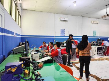 Makassar, 5 Nisan 2024 - Teknik bir sınıfta elektronik ve robotik projeler üzerinde çalışan öğrenciler, aygıt montajı ve öğretmen denetimi altında işbirliği