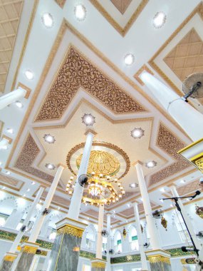 Büyük avizeler, mermer sütunlar ve ayrıntılı desenlerle süslü İslami tavanlar Darussalam Camii 'nin içini zarif ışıklandırma ve kaligrafi ile süslüyor..