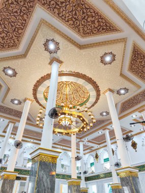 Büyük avizeler, mermer sütunlar ve ayrıntılı desenlerle süslü İslami tavanlar Darussalam Camii 'nin içini zarif ışıklandırma ve kaligrafi ile süslüyor..