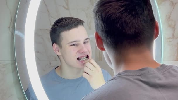 Cute Teenage Boy Limpiando Sus Aparatos Ortopédicos Frente Espejo Del — Vídeo de stock