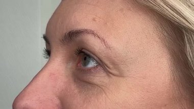 Orta yaşlı bir kadının kırışıklıklarıyla çevrili gözler. Bakışı yön değiştiriyor, bir şeyi takip ediyor..