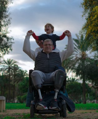 Ailesinin parkta oynaması, çocuğun babasının tekerlekli sandalyesine yaslanıp, bir insan kulesi yaratarak kahkahalarla gülmesine neden olur..