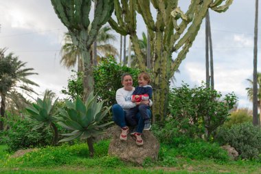 Anne ve oğul parkta gözlerden uzak bir yerde mutlu bir şekilde poz veriyorlar.