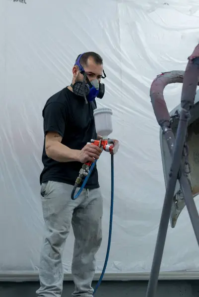 professional painter in the process of spray booth painting with pressure spray gun