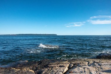 Arka planda mavi gökyüzü olan Kanada Denizi 'nin Rocky sahili.