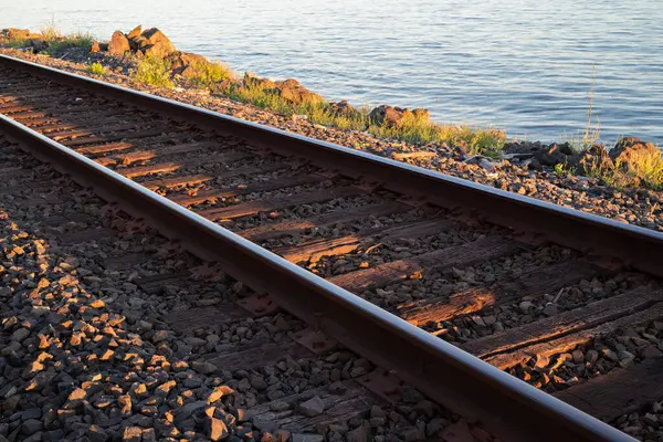 Yazın gün batımında deniz kıyısındaki tren rayları.
