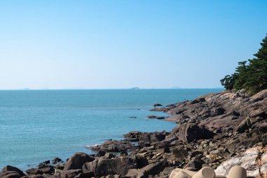 Denizin kayalık kıyıları ve mavi gökyüzü. Doğa bileşimi.