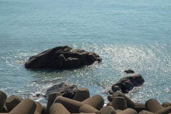 Denizde dalgalar birleştiğinde kırılan büyük bir kaya.