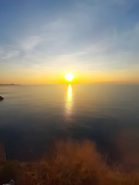Sakin bir denizin üzerinde huzurlu bir günbatımı canlı renkleri ve uyandırdığı huzurlu atmosferiyle dikkat çeker..