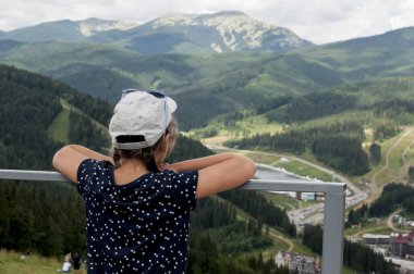 Kız yeşil dağlara bakıyor.