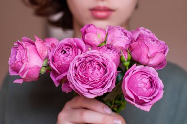 Kız elinde pembe güller tutuyor.