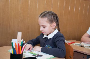 Liseli kız okulda bir kitap okuyor.