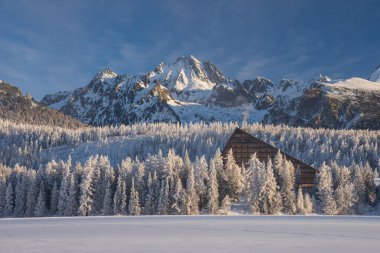 Strbske Pleso 'daki popüler otel, High Tatras, Slovakya. Ön planda donmuş göl, antetli yer, arka planda dağlar ve ağaçlar var. Hiç kimse yok..