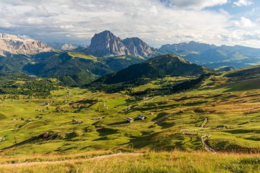 Seceda Dağı 'ndan Val Gardena' ya, güneşli yaz gününde İtalyan Dolomitleri 'ne yeşil çimenler ve bulutlu mavi gökyüzü..