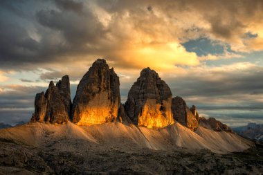 Ünlü kayalık Tre Cime di Lavaredo (Drei Zinnen) yaz akşamı ve günbatımında tepelerin üzerinde renkli bulutlarla. Mekan İtalyan Alpleri Güney Tyrol, Avrupa. Popüler turistik cazibe.
