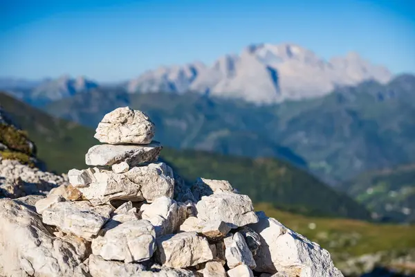 Pile of stones against blurry Marmolada peak with glacier in Dolimites mountains, Italy during summer clouless morning