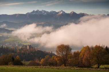 Polonya, Czorsztyn 'den renkli ağaçlı sonbahar manzarası. Eski kale ve Tatra Dağları arkasında, Pieniny ve sis önplanda.
