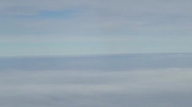 Bir uçak penceresinden, bulutlar yukarıdan ve aşağıdan görünür, ama ortada değil, bulutlardaki bir boşluktan geçme illüzyonunu yaratır.