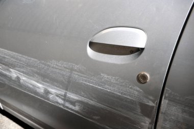 Trafik kazasının detaylarıyla dolu bir araba kapısı. Kapısı kazayla çizilmiş bir araba. Araba sigortacısı için kavramsal görüntü.