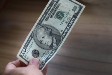 Satın alma ücretini 10 dolar banknotla ödeyen kişi. Nakit ödenmek üzere bir fatura tutuyor. Müşteri ödeme yapıyor. Eldeki para.