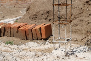 Ev yapım aşamasında. Bir inşaat alanında demir kiriş ve kırmızı tuğlalar. Bir bina inşaatı. İnşaat, duvarcılık, mimarlık kavramı.