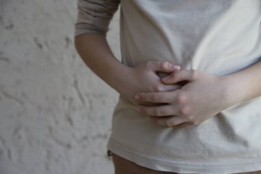 Sindirim sorunları olan hasta çocuk. Midesi ağrıyan bir çocuk. Mide sorunları olan bir genç. Gastrobağırsak hastalığı. Kopyalama alanı ve ışık renklerine sahip resim.