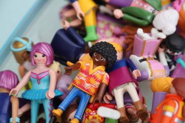 Afro-Amerikan Çocuk. İçinde Playmobil figürler olan bir kutu. Çocuklar için plastik bebekler. Oyuncak dolu bir kutu. koleksiyon figürleri. Peri bebekleri, prensesler, doktorlar, balerinler, rock yıldızları. Sarı elbiseli kız..
