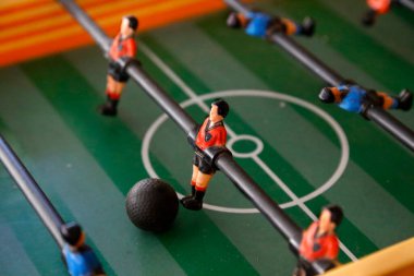 Langırt. Futbol salonu maçı. Geleneksel oyun. Futbol maçı. Futbolcularla dolu bir masa. Eski ahşap langırt. Futbolcular. Mavi ve kırmızı tişörtlü bebekler. Göktaşı