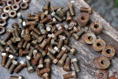 Paslı fındık, vida ve civata. Kirli. Eski model. Yaşlandım. Paslı metal parçaları birbirine uyuyor. Makine yapmak için nesneler. Elle çalışma tablosu.