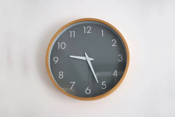 Minimalist stil duvar saati. Kuzeyli. Modern tasarım. İğneli ahşap saat. Bir saat. Dokuzu yirmi beş geçiyor. Ofis saati. İzole edilmiş beyaz. Sayılar. - Beyaz. Gri arka plan. Ağaç kenarı Süre