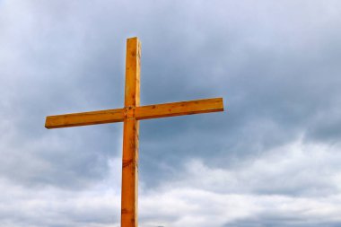 Arka planda gökyüzü olan ahşap haç. Hıristiyanlığın dini sembolü. Katolik Haçı.