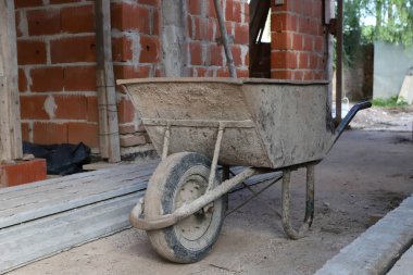 Ev inşaatında el arabası. Tuğlacılar ve inşaatçılar için yükleme aracı. İnşaat ve duvarcılığın kavramsal görüntüsü.