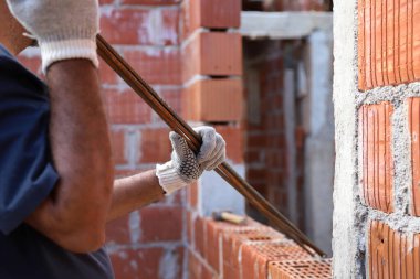 Mason ütü taşıyor. İnşaat alanında çalışan bir inşaatçı. Ev inşaatında çalışan profesyonel bir duvarcı. Mimarlık, inşaat, endüstri, inşaat işçisi, iş, insan