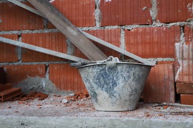 Mason 'ın kovası şantiyede. Seramik tuğlaları ve çimentoyla yapılmış bir ev. Binalar, evler, duvarcılık işleri kavramı.