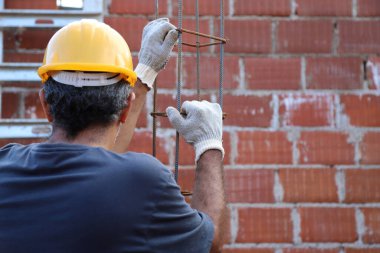 Ev inşaatında çalışan profesyonel bir duvarcı. İnşaat işçisi inşaat alanında demir kiriş taşıyor. İnşaat alanında çalışan bir inşaatçı. Mimarlık ve endüstri kavramı.