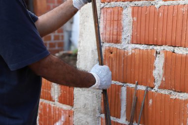 Mason demirle çalışıyor. İnşaat alanında çalışan bir inşaatçı. Ev inşaatında çalışan profesyonel bir duvarcı. Mimarlık, inşaat, endüstri, inşaat işçisi, iş, insan