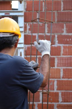 İnşaat işçisi inşaat alanında demir kiriş taşıyor. İnşaat alanında çalışan bir inşaatçı. Ev inşaatında çalışan profesyonel bir duvarcı. Mimarlık ve endüstri kavramı.