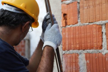 Mason ütü taşıyor. İnşaat alanında çalışan bir inşaatçı. Ev inşaatında çalışan profesyonel bir duvarcı. Mimarlık, inşaat, endüstri, inşaat işçisi, iş, insan