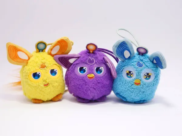 Furby 'ler. Mor, mavi ve sarı kürklü. Çocuklar için pelüş oyuncak. Aynı zamanda bir yapay zeka oyuncağı. Şefkatli gözlerle. Kürklü bebek.