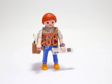 Playmobil doll. Newsboy. New's paper seller. Young boy. Paperboy. Newspaper. Redhead with freckles. Boy. Employee. Happy person. Isolated white. Toy. clipart