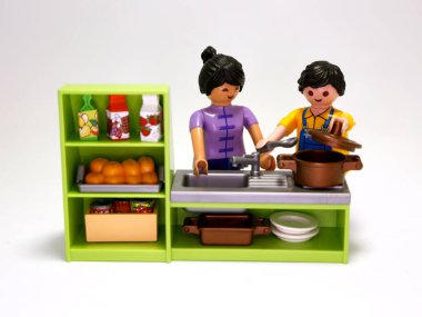 Oyuncak bebekler. Bir çift yemek. Kadın ve erkek yemek yapıyor. Aile mutfaklarında. Yemek hazırlama. Çok kültürlü bir çift. Çocuklar için oyuncaklar. İzole edilmiş beyaz.