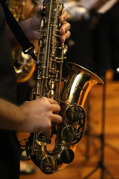 Bir klasik müzik konserinde saksafon çalan müzisyen. Birinin ellerinin saksafon çalarkenki görüntüsü. Rüzgar müzik aleti.