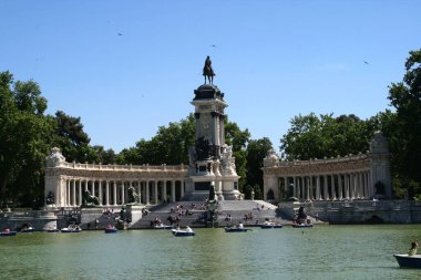 El Retiro Parkı 'ndaki göl, Madrid, İspanya. Güneşli bir günde insanlar gölde yelken açıyor..