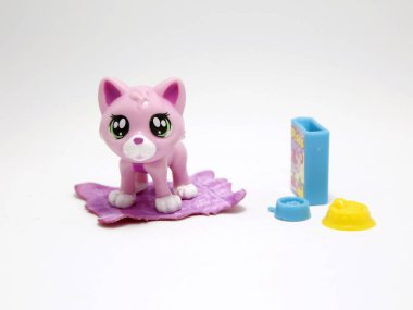 Pembe kedi evinde, su ve yiyecekleriyle birlikte. Evcil hayvan. Kawaii gözleriyle oynaması için sevimli bir kedi yavrusu. Çocuklar için oyuncaklar.