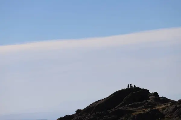 stock image People on top of a mountain backlit during sunset. Adventurers on a hill. Concept of adventure tourism, hiking, climbers. Group of sports friends. Sky background with copy space.