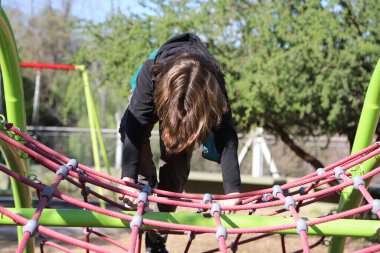 Çocuk parkında dağcıda oynayan sarışın çocuk. Dışarıdaki çocuk parkında. Çocuk parkı..