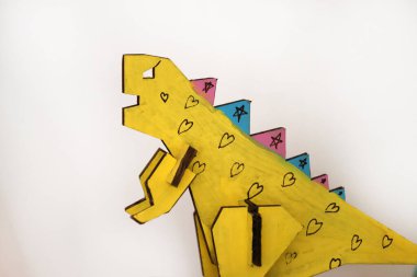 Çocuklar tarafından boyanmış el yapımı karton dinozor. Mukavva içinde üç boyutlu çocuk el işi. Kopyalama alanı olan izole edilmiş beyaz arkaplan.