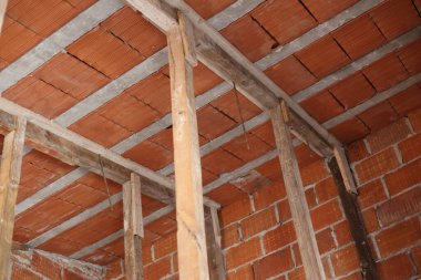 İnşaat devam ediyor. Ahşap kirişleri ve direkleri destekleyen kırmızı seramik tuğla çatı. İnşaat endüstrisi.